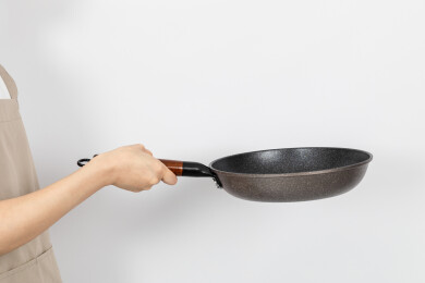 一只手拿着空的麦饭石平底锅颠锅动作