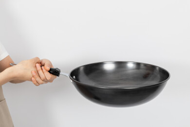 一只手拿着空的铁炒锅颠锅动作