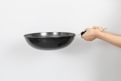 一只手拿着空的铁炒锅颠锅动作