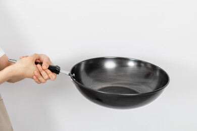 一只手拿着空的铁炒锅颠锅动作
