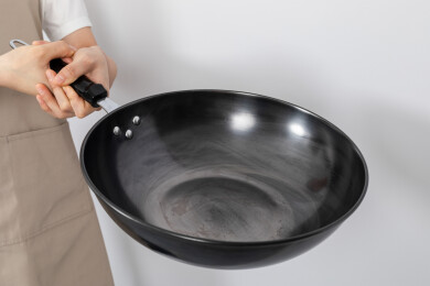 一只手拿着空的铁炒锅颠锅动作