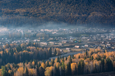 秋季清晨的中国新疆禾木村晨雾与炊烟