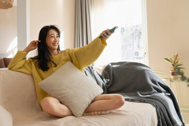 一位青年女人坐在客厅的沙发上看电视