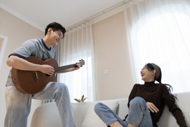 一对年轻情侣坐在沙发上弹吉他