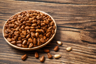 一盘松子摆放在木桌上周围散落着剥开的松子