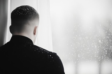 男子凝望窗外雪景