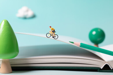 微缩创意骑着自行车在课本上加速冲刺的考生