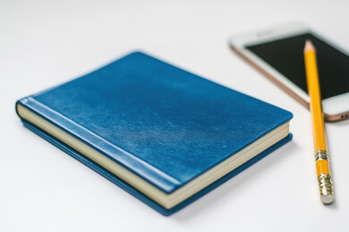 正上方白色背景下的螺旋笔记本和铅笔照片