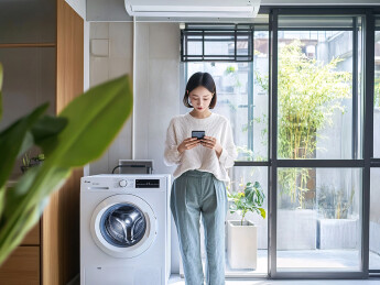 阳台洗衣机旁使用手机的简约女性人物图片