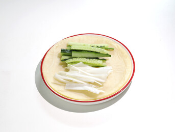 白色桌面上一盘北京烤鸭的配菜卷饼葱丝青瓜