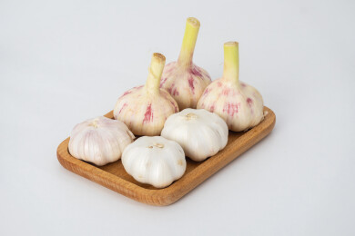 白色背景上木盘里装着新鲜采摘的生蒜和晾晒