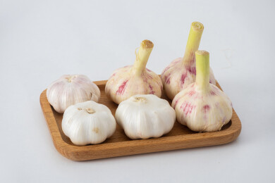 白色背景上木盘里装着新鲜采摘的生蒜和晾晒