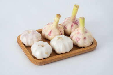 白色背景上木盘里装着新鲜采摘的生蒜和晾晒