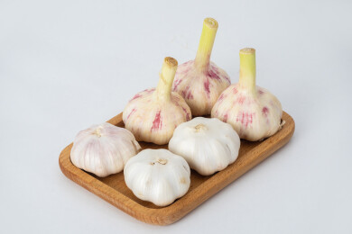 白色背景上木盘里装着新鲜采摘的生蒜和晾晒
