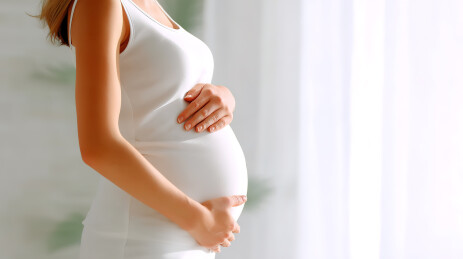 穿着白色孕妇装的孕妇腹部特写