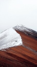 雪覆山峰与红土坡的对比