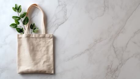 大理石面放着麻布手提袋和绿色枝叶