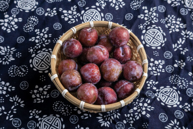 桌面篮子里堆满的青红脆李子生鲜水果