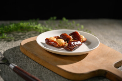 桌面上的盘子里的美味可口的椰枣夏威夷果仁