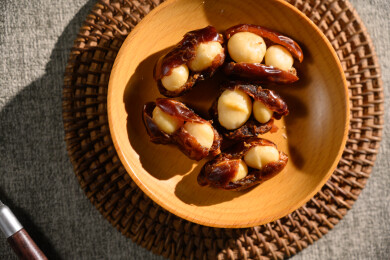 桌面上的盘子里的美味可口的椰枣夏威夷果仁