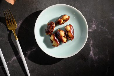 桌面上的盘子里的美味可口的椰枣夏威夷果仁