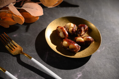 桌面上的盘子里的美味可口的椰枣夏威夷果仁