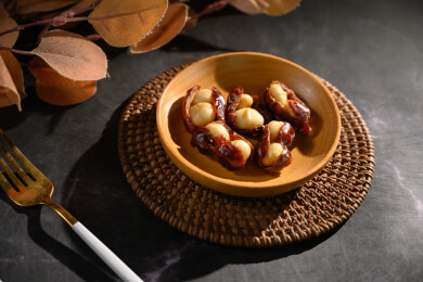 桌面上的盘子里的美味可口的椰枣夏威夷果仁