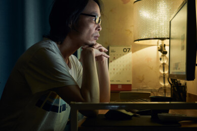 坐在电脑桌前面对屏幕的男子