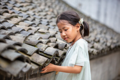 古巷中小女孩在古屋瓦片旁在玩耍微笑