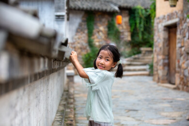 古巷中小女孩在古屋瓦片旁在玩耍微笑