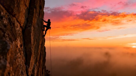 攀岩者夕阳下挑战峭壁