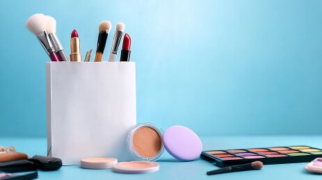 化妆刷与彩妆品摆放在蓝色背景前的静物场景