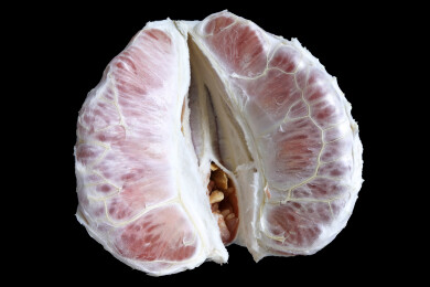 黑色背景上一个剥开的中秋节美食水果红柚子