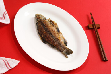 红色桌面上一盘子中餐家常菜美食煎鱼