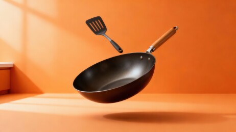 橙色背景下的悬浮炒锅与铲子