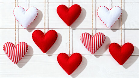 红色白色心形挂饰悬挂在木板背景上