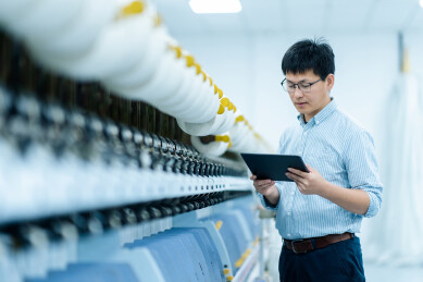 工厂车间技术人员手持平板检查纺纱机设备