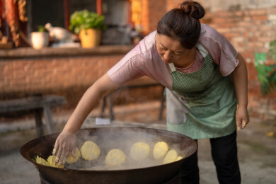 乡村的一位中年女人在院子里做饭