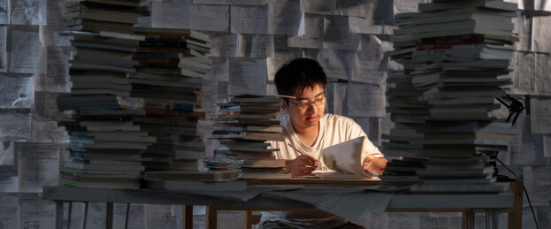 疲惫的学生在浩瀚的书海中写作业