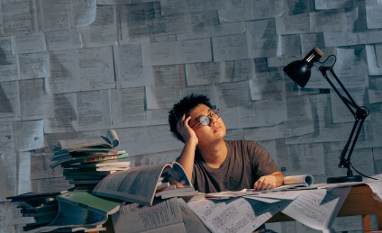 疲惫的学生在浩瀚的书海中写作业