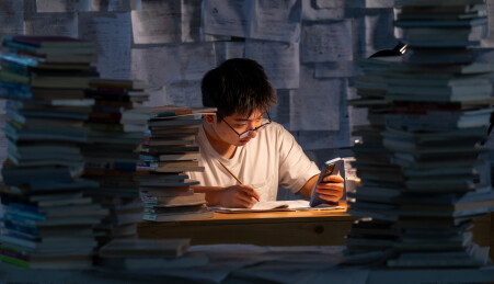 疲惫的学生在浩瀚的书海中写作业