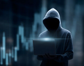 黑客持电脑在金融数据背景前