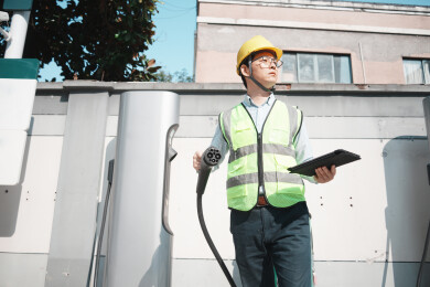 戴安全帽男子手持充电枪检查充电桩