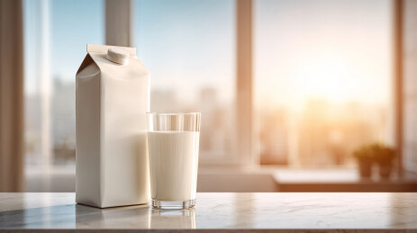 晨光下大理石台面上的牛奶盒与玻璃杯