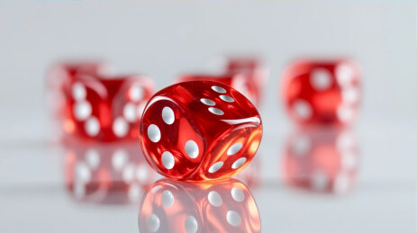 红色透明骰子在白色反光面上静止摆放