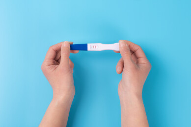 手拿验孕棒特写蓝色背景