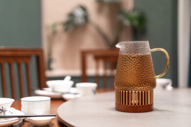 锤纹玻璃茶壶置于圆桌茶具旁