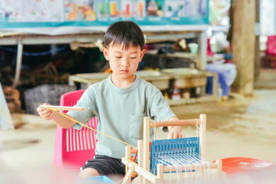亚裔儿童在西双版纳曼掌村体验传统手工织布