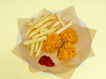 油炸食品炸鸡薯条不健康食物在浅黄色背景上