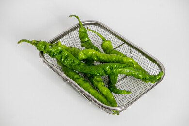 白色背景上金属菜篮子里的螺丝椒辣椒食材